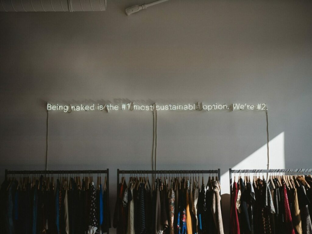 Photo of the inside of a charity shop with a neon sign saying, 
